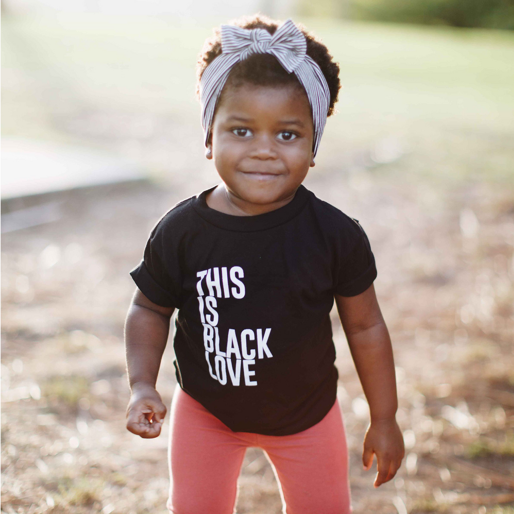 "This Is Black Love" short sleeve onesie. Little girl wearing 100% Cotton unisex design for toddlers.